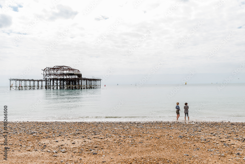 Day view of two women over Brighton Pier after fire