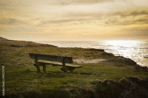 Bench on sea coast at sunset
