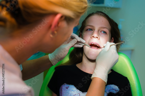 Close up of girl having his teeth examined by a dentist - dental caries prevention