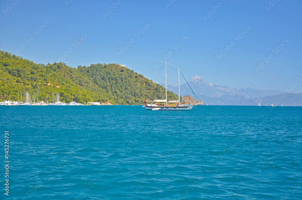 Obraz premium The ship on the background of the bright blue Mediterranean sea and the mountains
