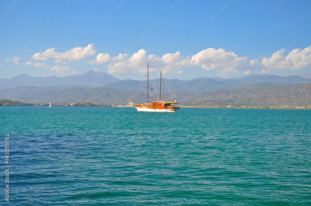 The ship on the background of the bright blue Mediterranean sea and the mountains