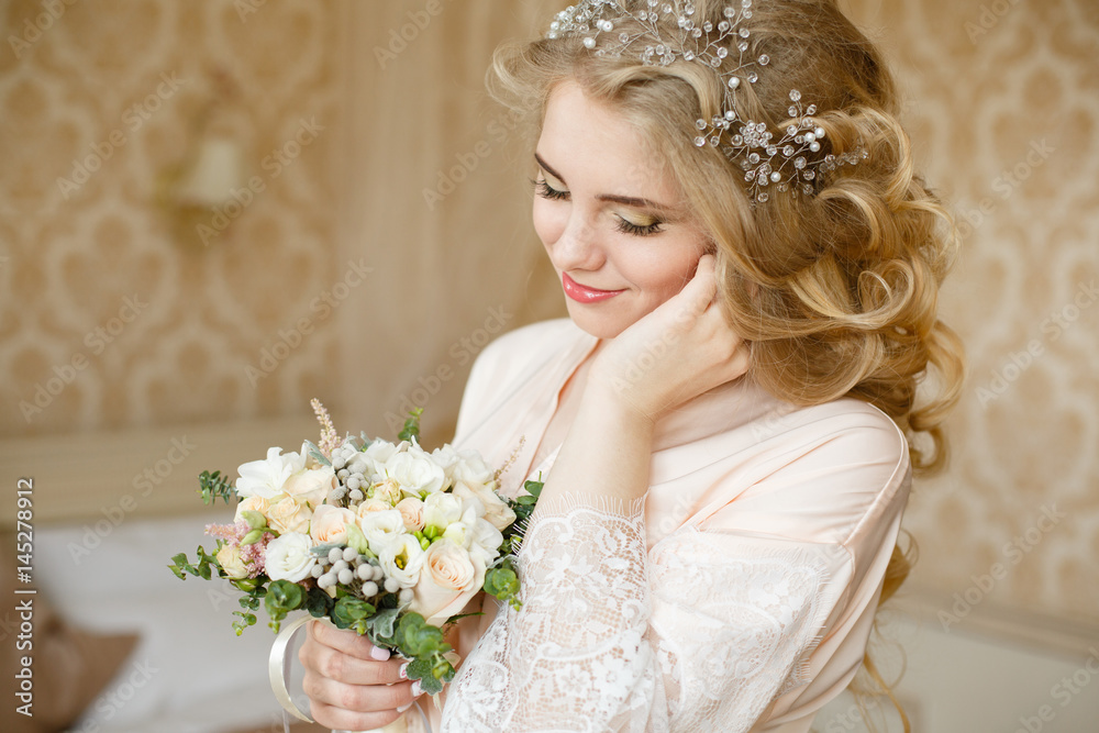 Obraz premium Pretty young girl. Blonde woman with luxurious long curly hair. Boudoir morning of the bride. Taking wedding bouquet in her hands