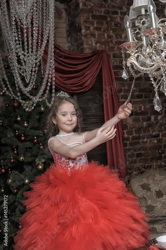 Little girl in red princess dress and chandelier with crystal