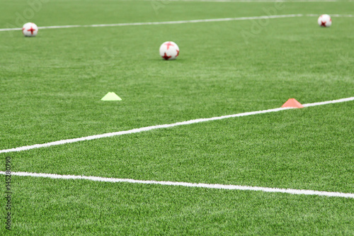Balls and chips for football training. Sports background. Artificial lawn with markings on a soccer field.