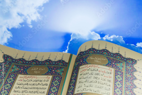 Opening pages of holy book Qur'an with clouds photo