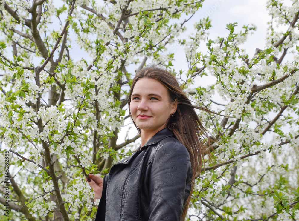 Beautiful fairy young girl in a flowering plum garden. Portrait of a girl on a white flowers background