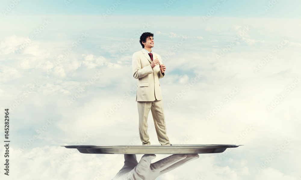Obraz premium Businessman on metal tray playing fife against blue sky background
