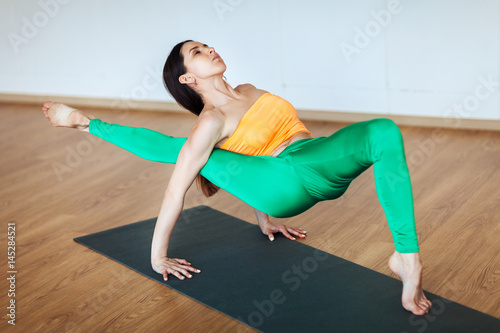 Young attractive woman practicing yoga, working out, wearing sportswear, orange suit, indoor photo