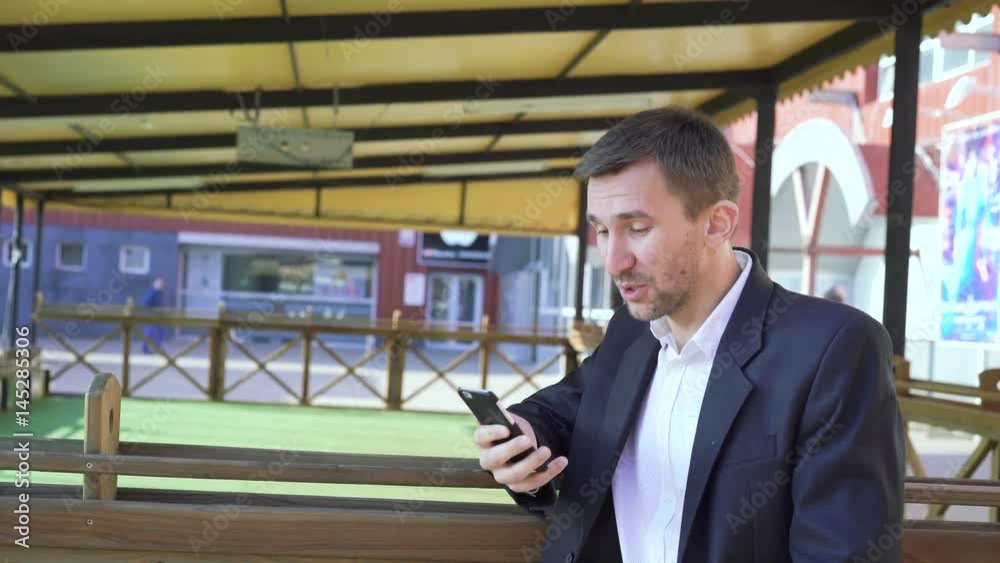 Smiling handsome man chatting on the smartphone on the street in sunny day 4K Smiling handsome man chatting on the smartphone on the street in sunny day 4K