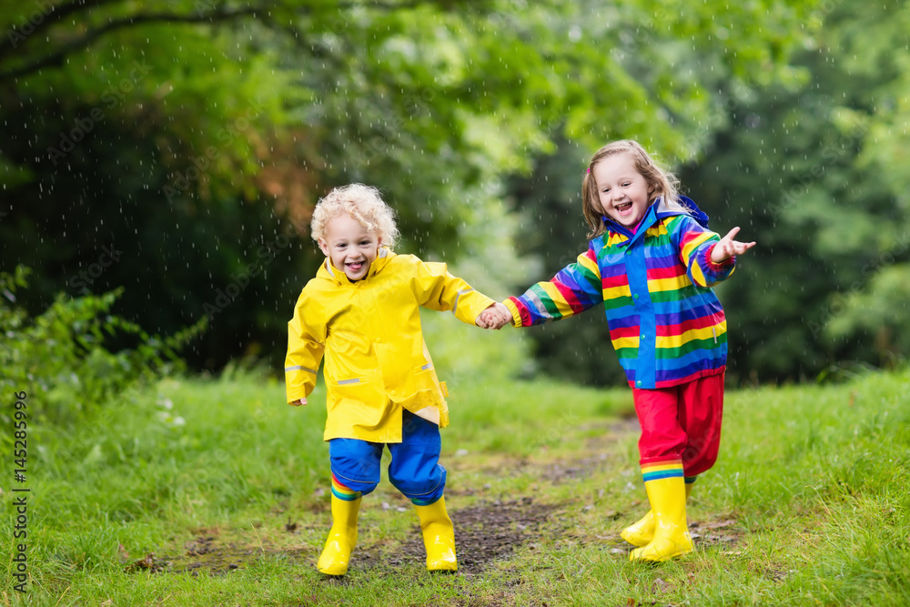 Kids play in rain and puddle in autumn Kids play in rain and puddle in autumn