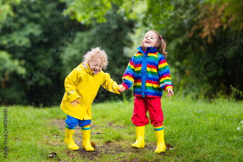 Kids play in rain and puddle in autumn