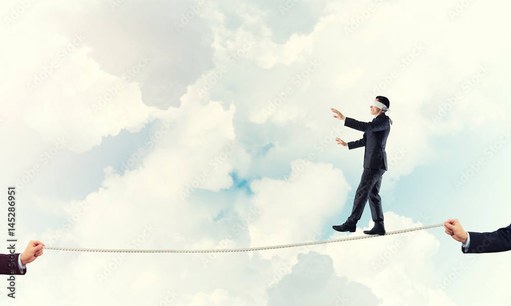 Business concept of risk support and assistance with man balancing on rope Business concept of risk support and assistance with man balancing on rope