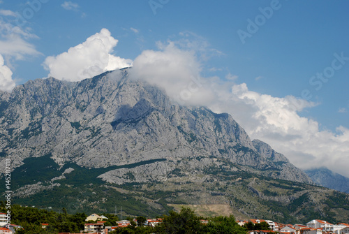 A small cloud on top of a mountain on a sunny day © Dmity