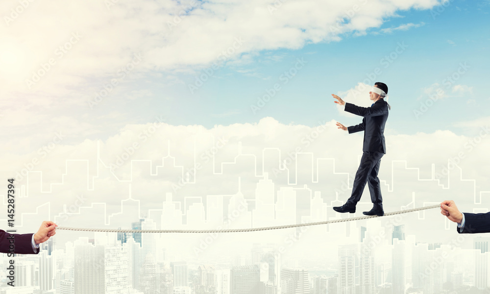 Business concept of risk support and assistance with man balancing on rope Business concept of risk support and assistance with man balancing on rope
