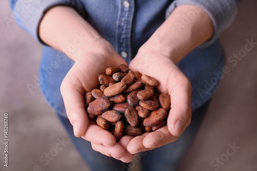 Female hands holding aromatic cocoa beans, closeup