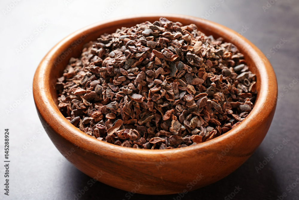 Bowl with aromatic cocoa nibs on gray table Bowl with aromatic cocoa nibs on gray table