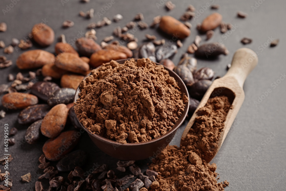 Bowl and wooden scoop with aromatic cocoa powder on gray background Bowl and wooden scoop with aromatic cocoa powder on gray background
