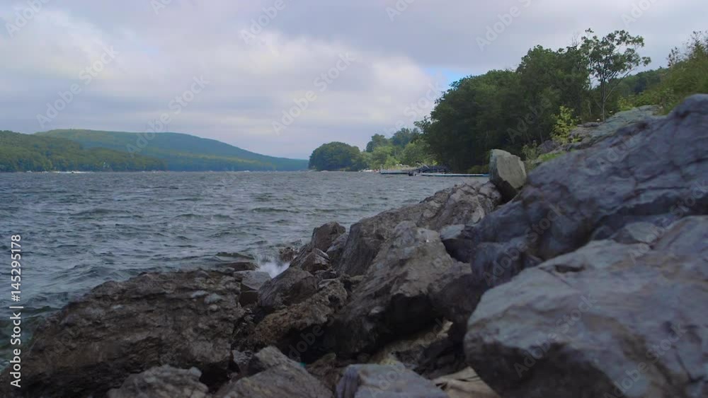 Waves Crashing on Rocks Near Lake During Cloudy Summer Day Waves Crashing on Rocks Near Lake During Cloudy Summer Day