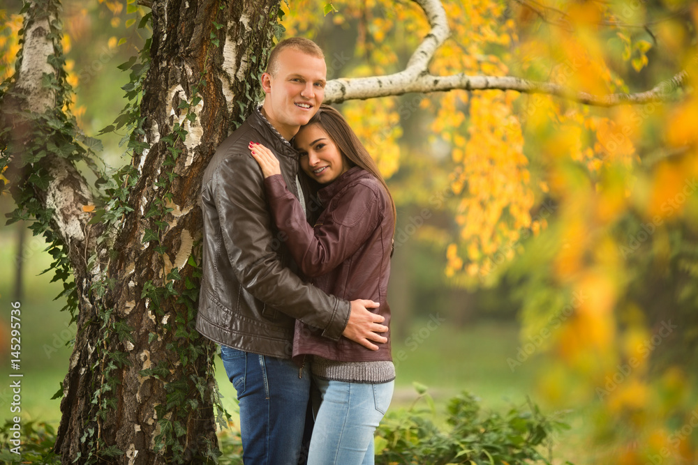 Happy young couple standing  in autumn park and holding each other