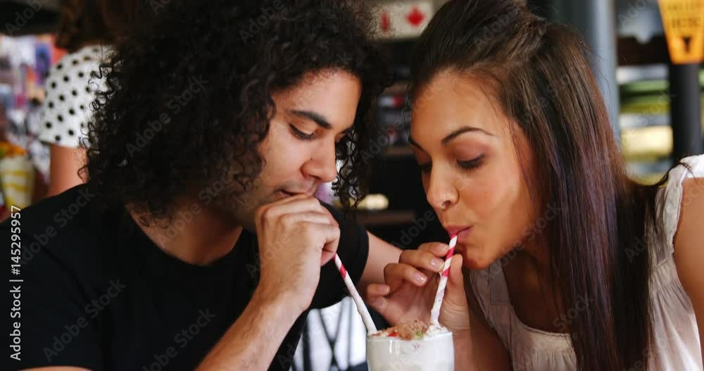 Couple drinking smoothie together with straw in pub Couple drinking smoothie together with straw in pub