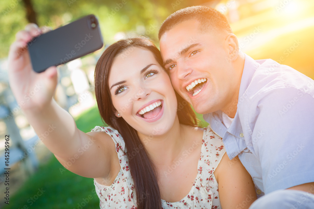 Happy Mixed Race Couple Taking Self Portrait with A Smart Phone in the Park. Happy Mixed Race Couple Taking Self Portrait with A Smart Phone in the Park.