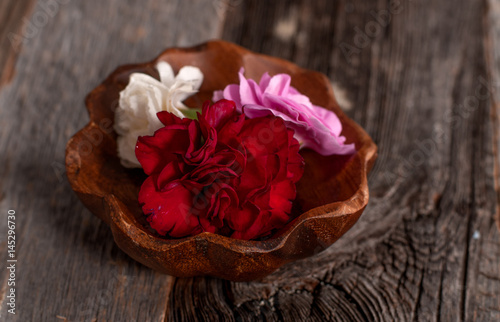 Spa Concept. Flowers in wooden bowl on table