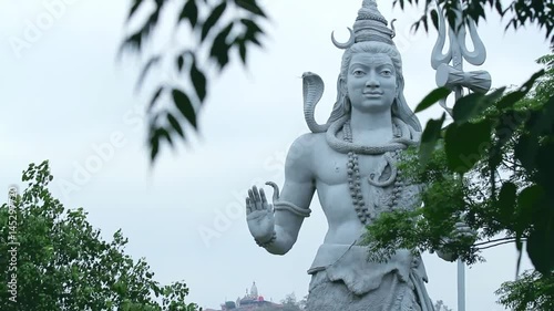 A large statue of the Hindu god Shiva looking over the ghats of Haridwar