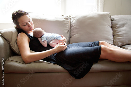 Young woman with newborn child on sofa