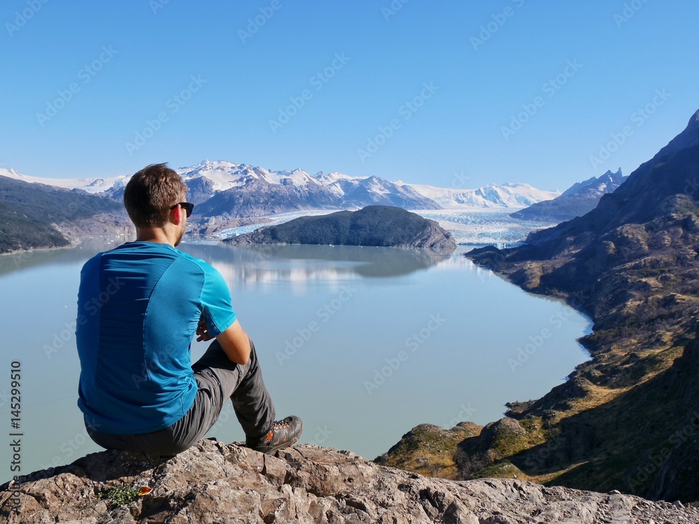 Naklejka premium Young man looking at lake and glacier