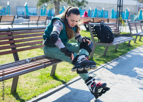 Beautiful young roller girl unscrewing wheels on freeskate roller Skates with Allen key or Hex key tool. Maintenance of professional skates photo