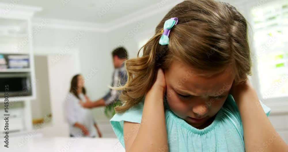 Girl covering his ears while parent quarreling in background Girl covering his ears while parent quarreling in background