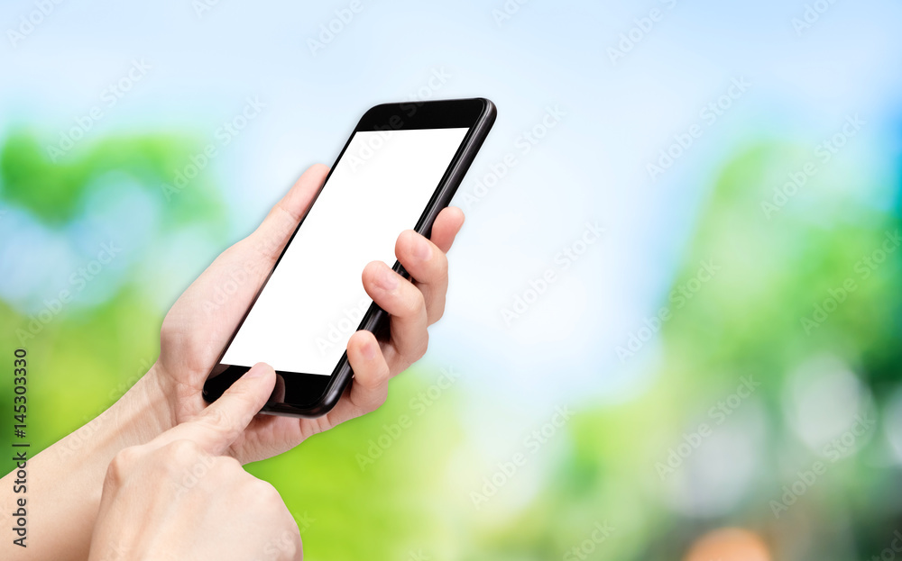 Hand click mobile phone with blur green tree background bokeh light,White screen mock up template for adding your design or your text