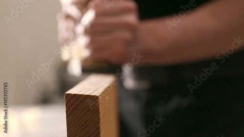 Close up shot of carpenter or joiner working with hand planer in wood workshop