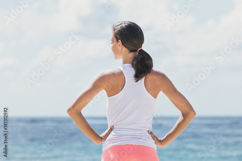 sporty woman warming up before workout with sea and skies at the background