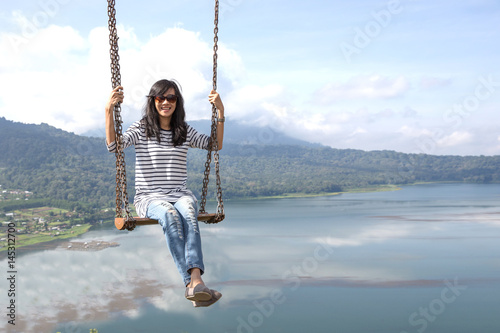 Carefree happy woman swinging on top of mountain edge cliff