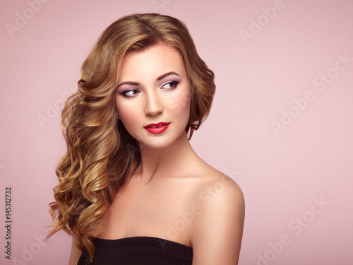 Blonde woman with long and volume shiny wavy hair . Beautiful model with curly hairstyle. Perfect make-up. Beauty style model