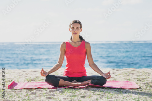 sporty young woman doing yoga meditation at the beach