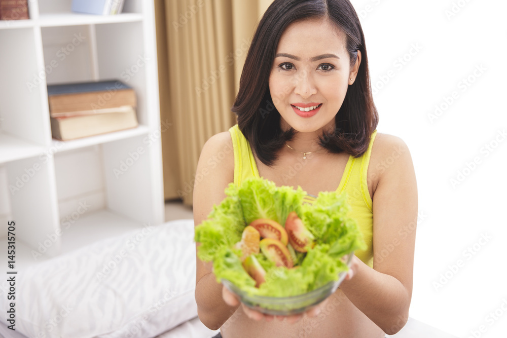 pregnant woman holding a bowl of fresh salad pregnant woman holding a bowl of fresh salad