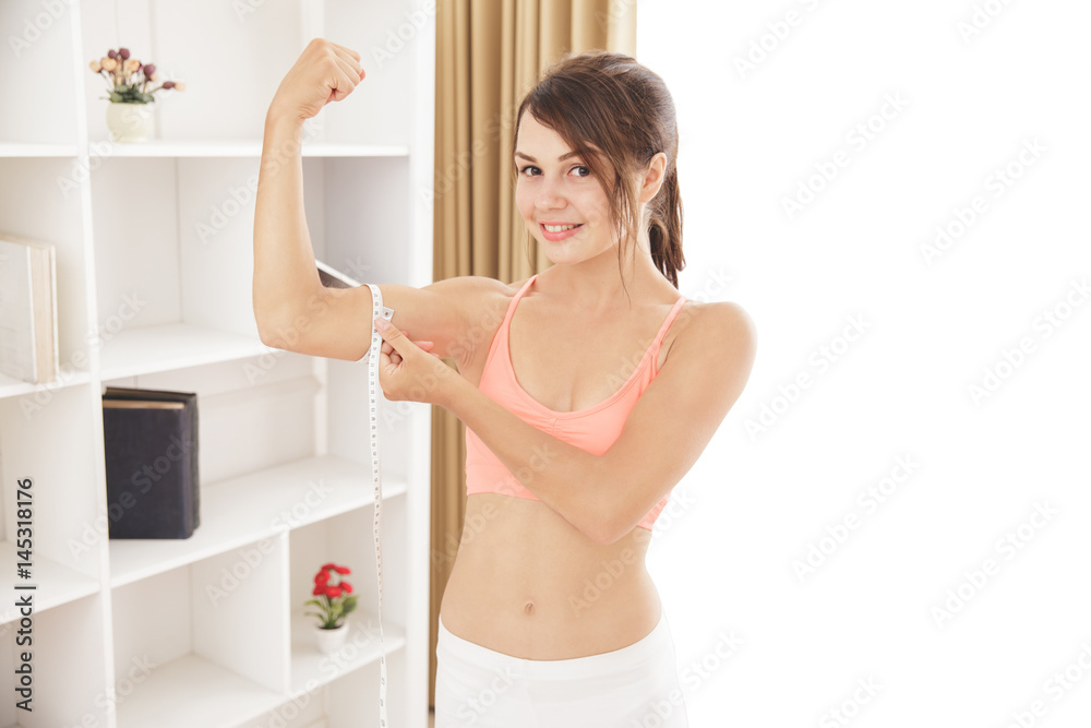 sporty woman smiling while measures her biceps with measuring ta sporty woman smiling while measures her biceps with measuring ta