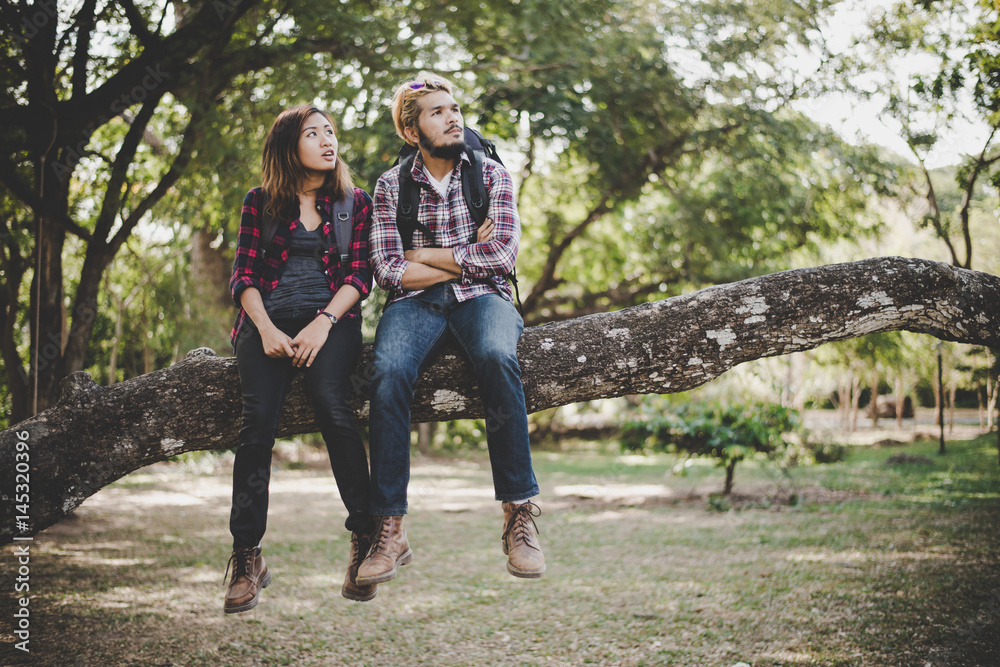 Young hikers couple take a rest sitting on branch enjoy with nature. Travel concept. Young hikers couple take a rest sitting on branch enjoy with nature. Travel concept.