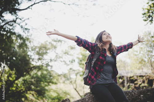 Young hiker woman sitting raising her arm on branch with backpack, Travel concept.