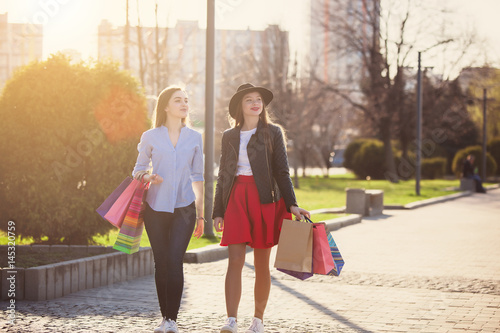 Two girls walking with shopping on city streets