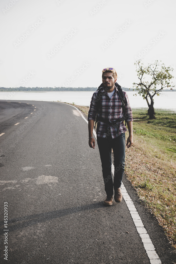Young tourist man walking on a countryside road. Young tourist man walking on a countryside road.