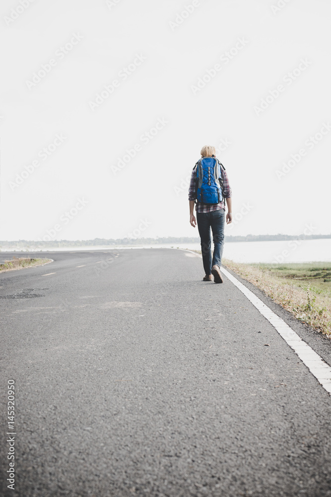 Young tourist man walking on a countryside road.
