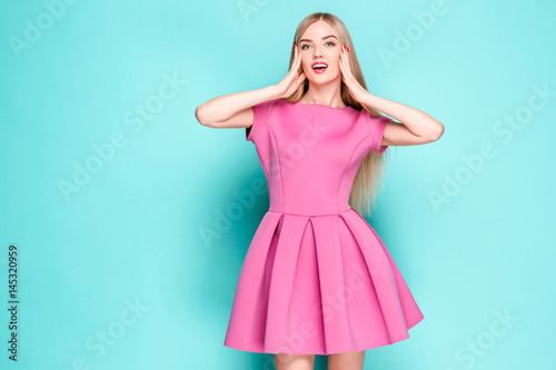 Smiling beautiful young woman in pink mini dress posing at studio © master1305