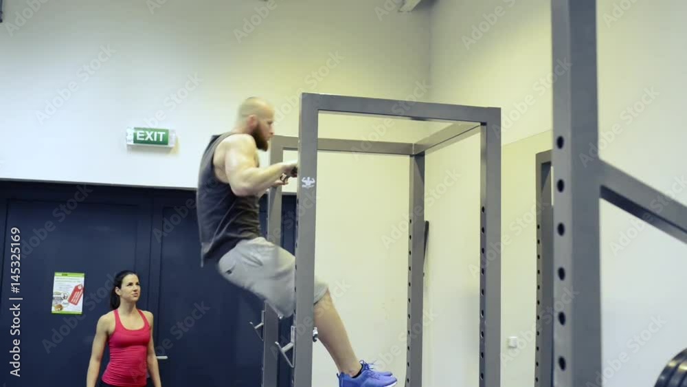 Man in gym working out, doing pull-ups on horizontal bar. Man in gym working out, doing pull-ups on horizontal bar.