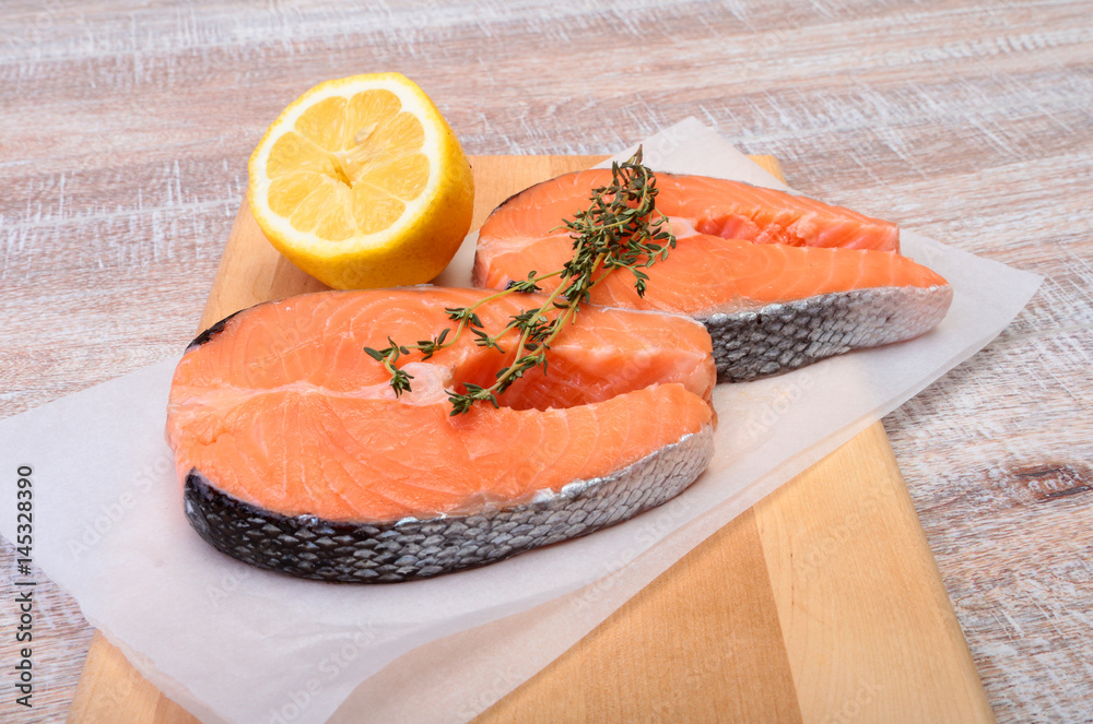fresh raw salmon with spices and lemon on wooden cutting board. ready for cookin fresh raw salmon with spices and lemon on wooden cutting board. ready for cookin