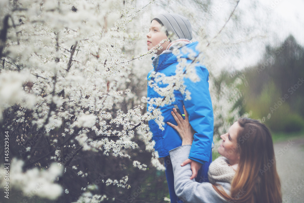 Obraz premium Mother and son smelling flowers in spring garden