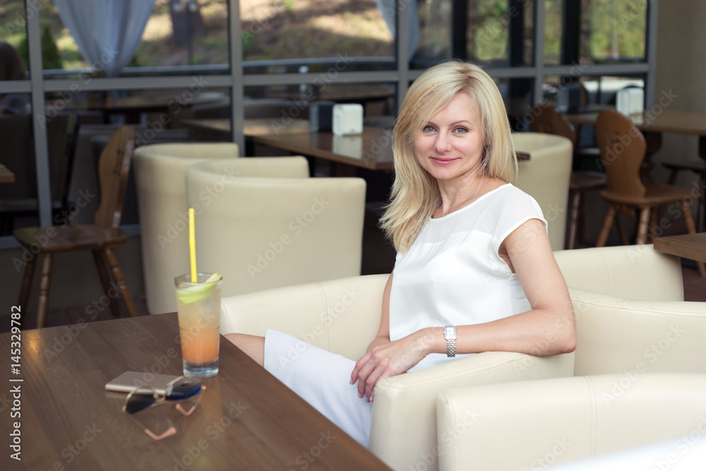 Beautiful blonde woman sits in a summer café
