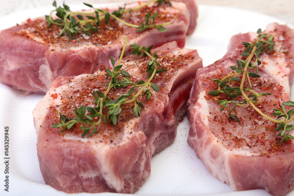 Raw pork chops, spices and rosemary on cutting board. Ready for cooking.